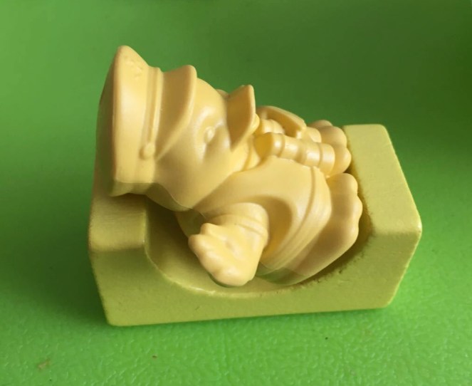 A small plastic yellow duck rests on an arched green wooden building block