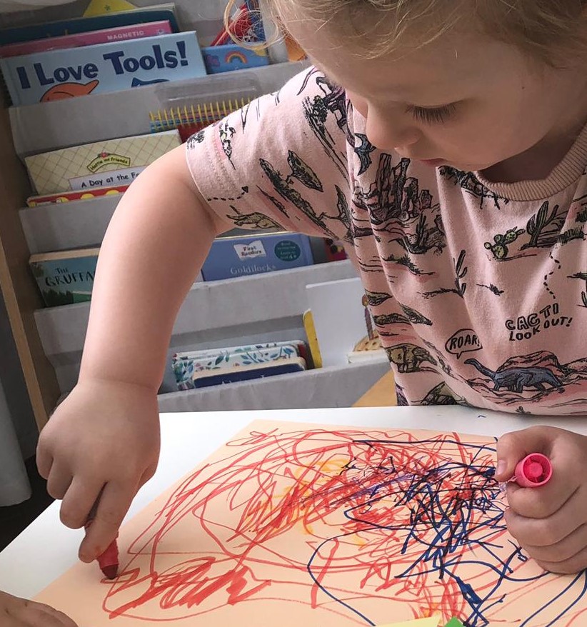 A child practising gripping and controlling a chunky pen during a drawing exercise