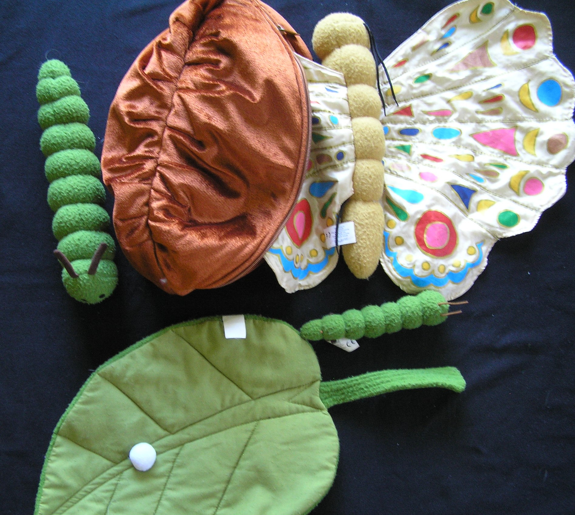 Soft toy caterpillar, cocoon and butterfly from within a library story sack for Eric Carle's The Very Hungry Caterpillar.