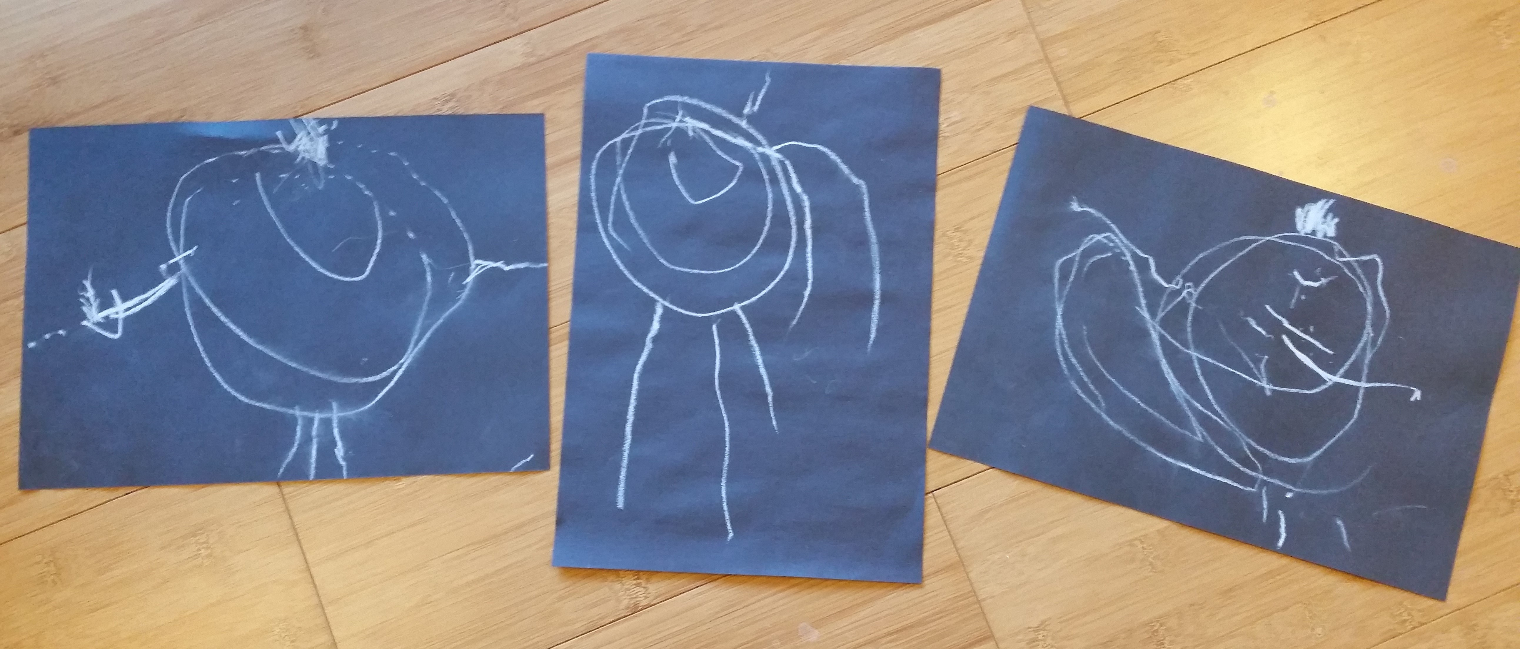 A set of three child's drawings made in chalk on black sugar paper.