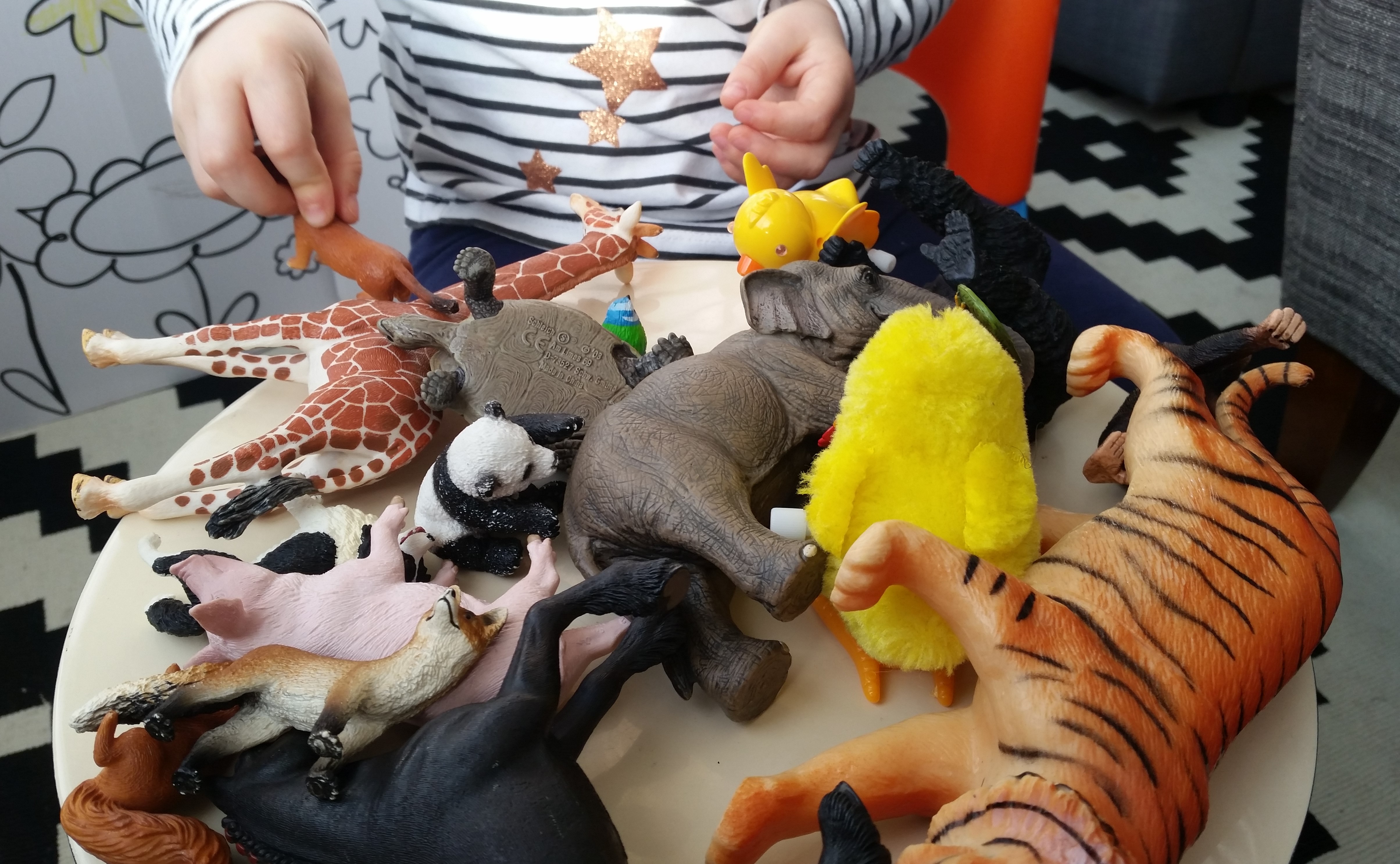 A young girl standing in front of a collection of toy animals.