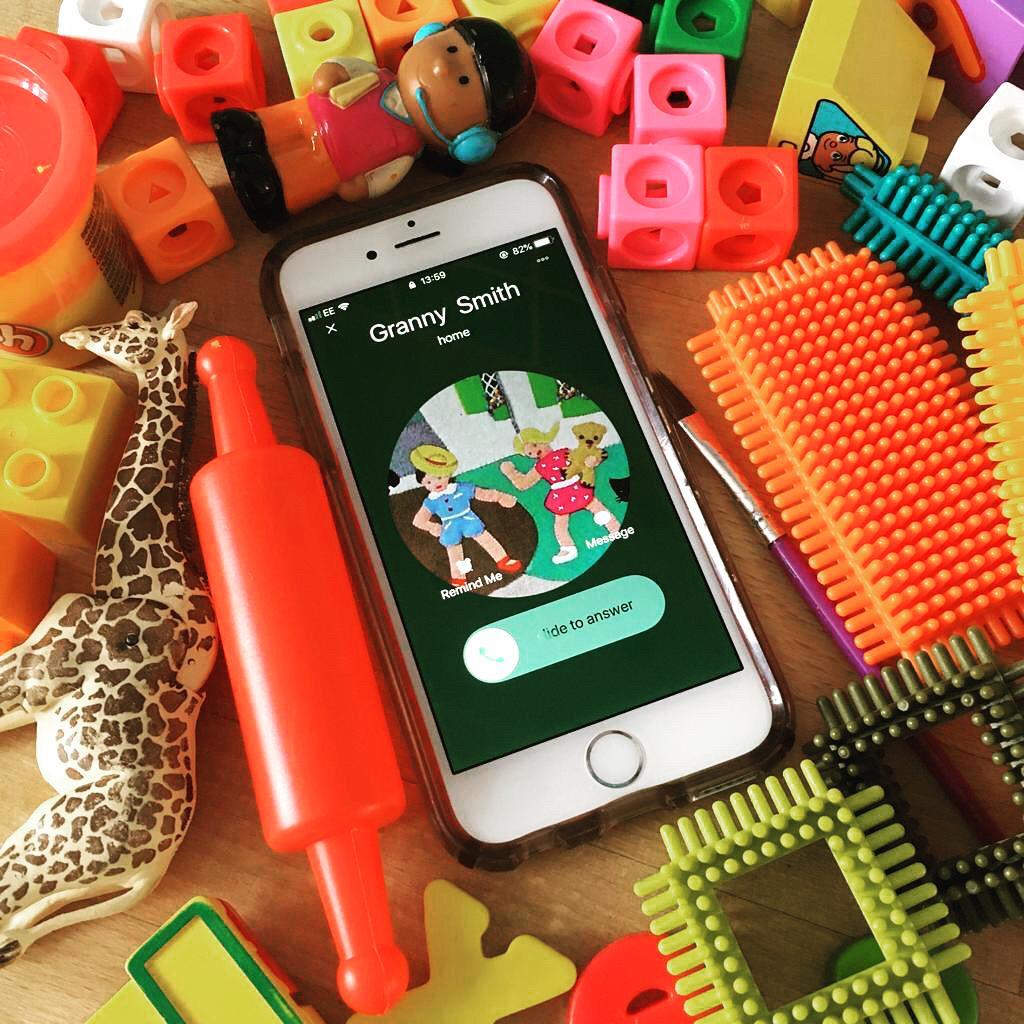 An Apple iPhone amid a pile of toys, showing an incoming call from Granny Smith