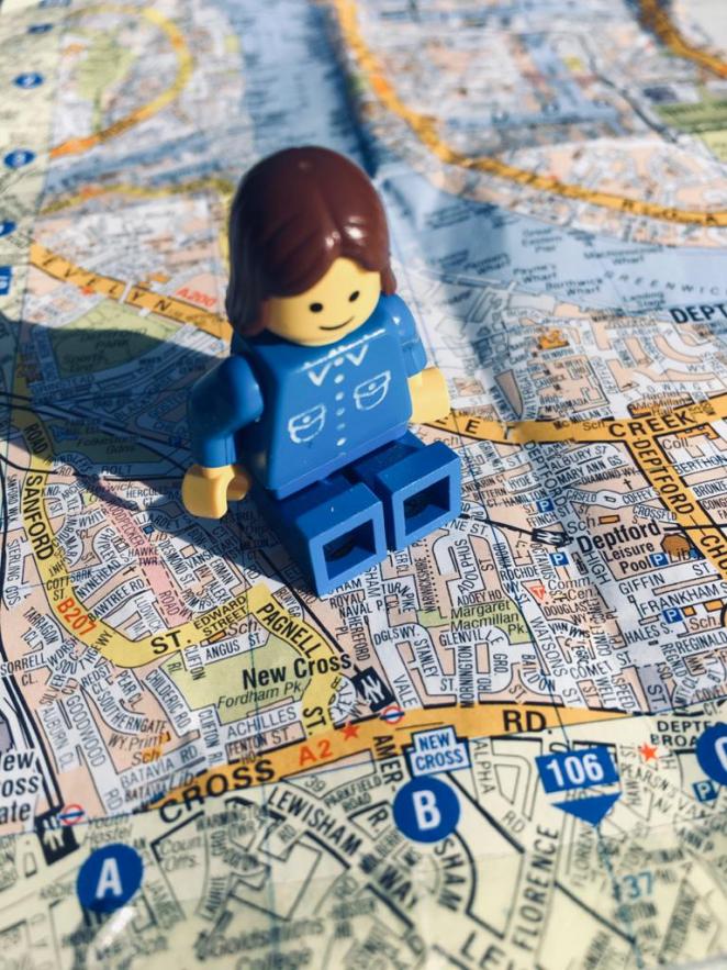 A female Lego minifigure sitting on a map of London