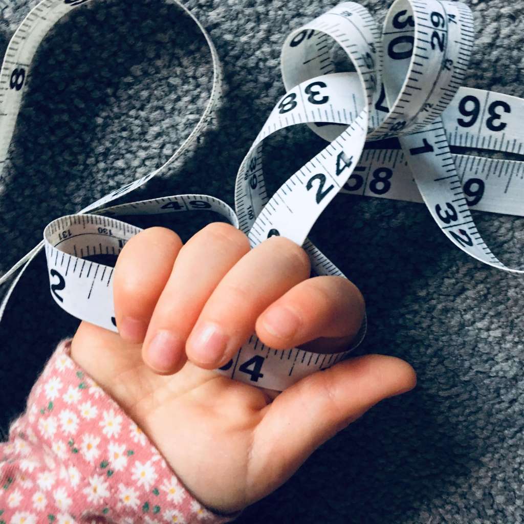 A child holds a coiled measuring tape in her hand