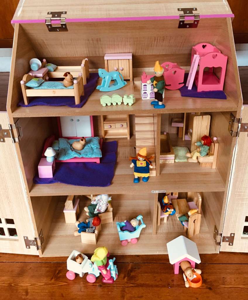 A child's wooden doll's house, populated with dolls and animals