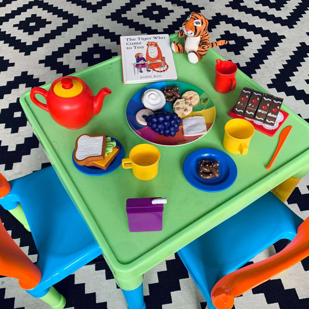 A child's table is set with pretend crockery, cutlery and food, as well as a copy of Judith Kerr's The Tiger Who Came to Tea and a cuddly toy version of the eponymous tiger