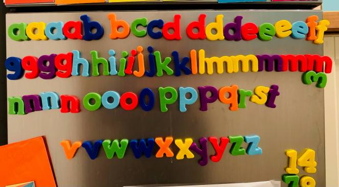 A selection of magnetic letters in alphabetical order on a fridge door