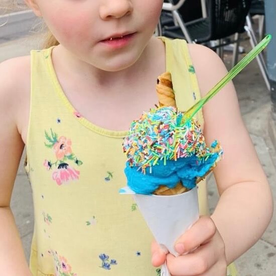 A child holding a bubblegum flavour ice cream cone