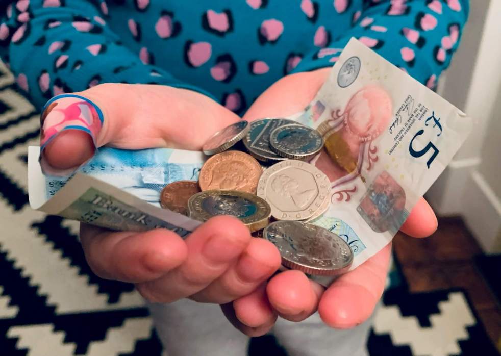 A child holding a handful of cash and coins