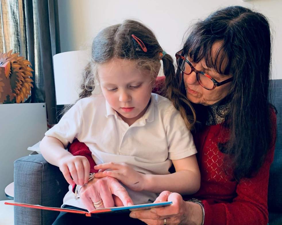 A young girl and her grandmother sit and read a book together