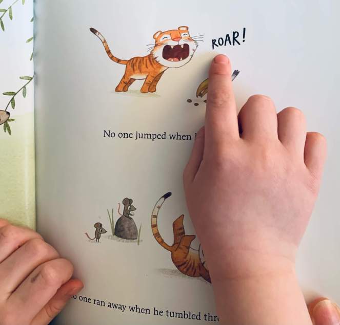 A child points to the word roar in the book The Tiptoeing Tiger by Philippa Leathers
