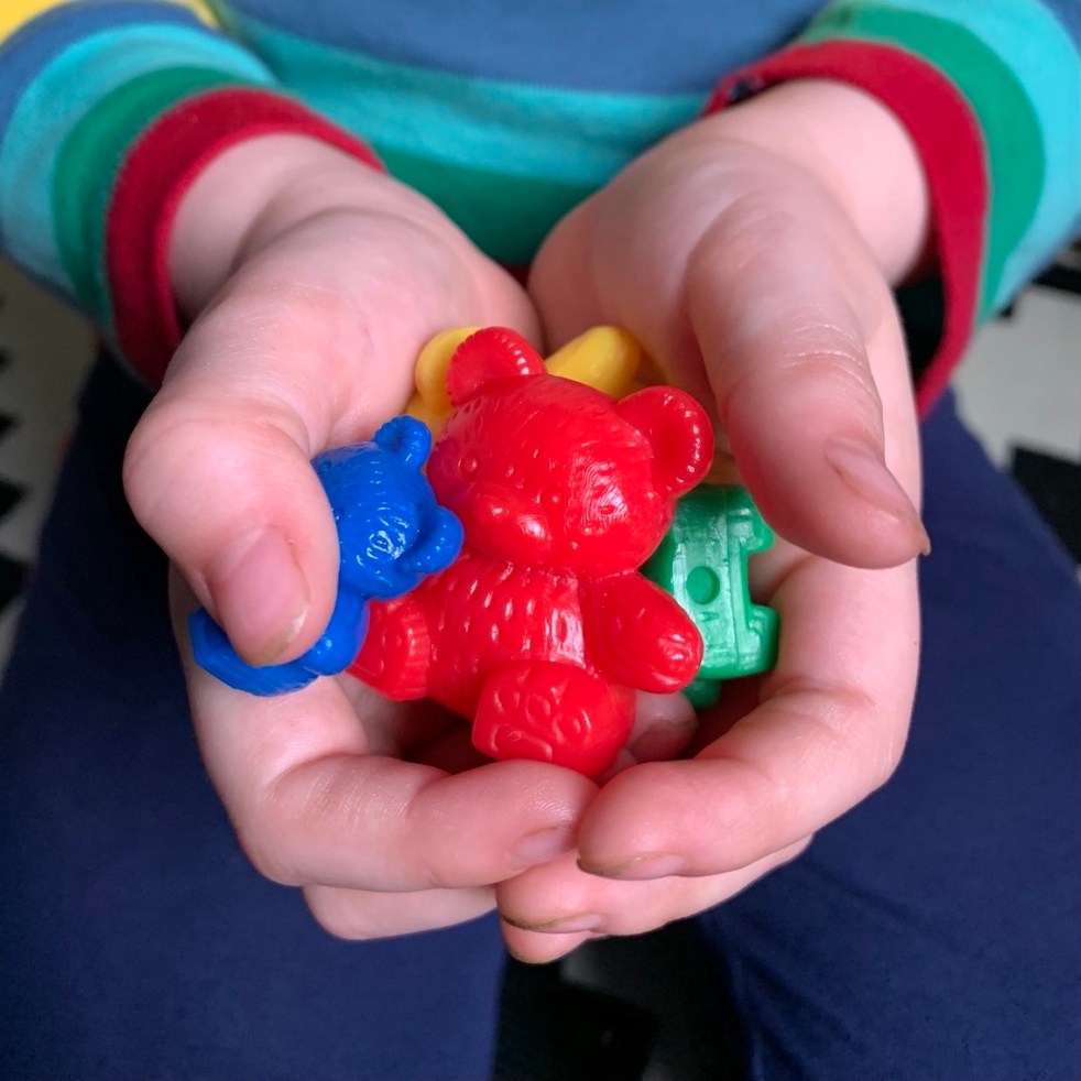 A child holding a handful of compare bears in cupped hands to illustrate a piece on subtilising