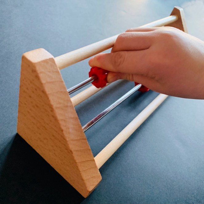 A child slides some two beads along the top row of Dutch counting frame called a rekenrek